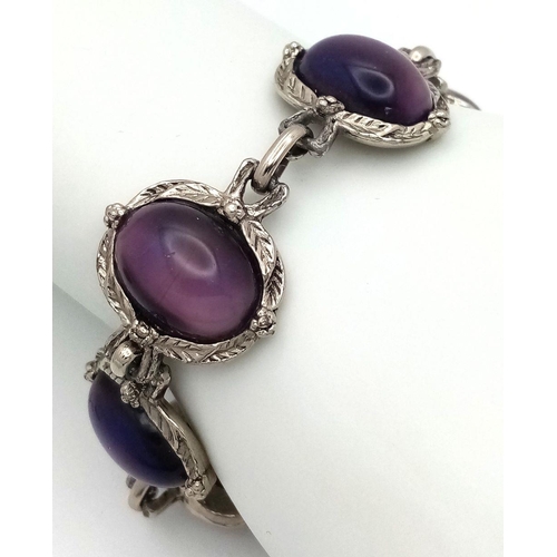 181 - A vintage, white metal (untested) bracelet with large cat’s eyes purple cabochons with exceptional l... 