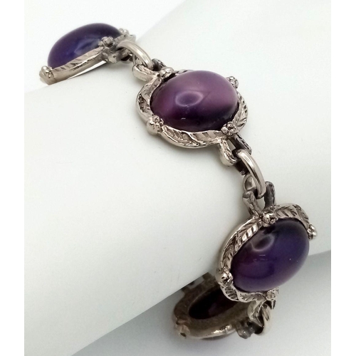 181 - A vintage, white metal (untested) bracelet with large cat’s eyes purple cabochons with exceptional l... 