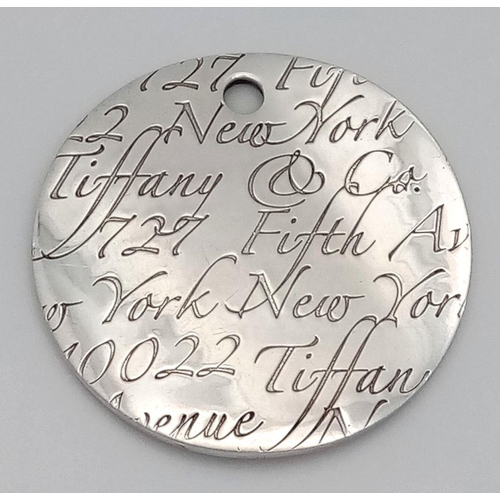 225 - A Tiffany and Co. Circular Fifth Avenue Inscription Pendant. 4cm diameter. 24.7g.