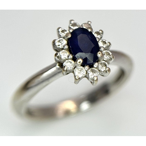 729 - A Classic Vintage 18K White Gold Sapphire and Diamond Ring. A deep blue oval cut central sapphire wi... 