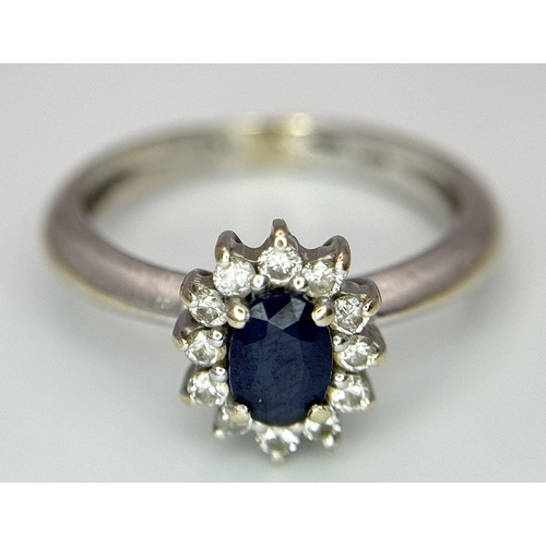 729 - A Classic Vintage 18K White Gold Sapphire and Diamond Ring. A deep blue oval cut central sapphire wi... 