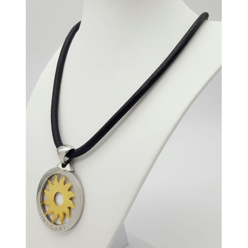 617 - A Bulgari Steel and 18K Yellow Gold Sun Pendant. 4.5cm diameter.  Textile necklace. Comes with origi... 