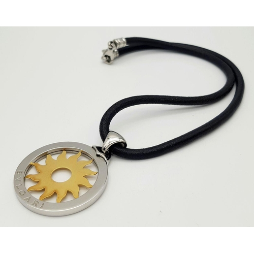 617 - A Bulgari Steel and 18K Yellow Gold Sun Pendant. 4.5cm diameter.  Textile necklace. Comes with origi... 