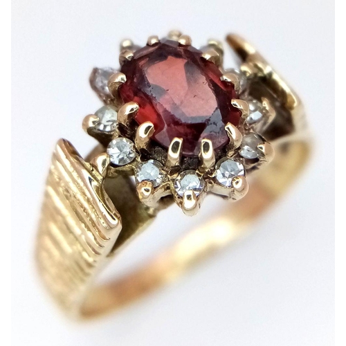 410 - A 9K Yellow Gold Garnet and Diamond Halo Patterned Band Ring, 0.12ct diamond weight, 0.55ct garnet w... 