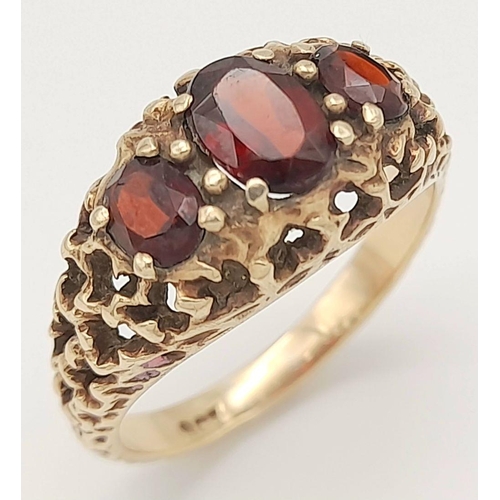 162 - An Antique 9K Yellow Gold Garnet Ring. Three rich garnets amongst a decorative cluster of gold. Size... 