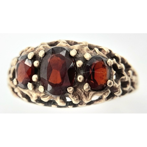 162 - An Antique 9K Yellow Gold Garnet Ring. Three rich garnets amongst a decorative cluster of gold. Size... 