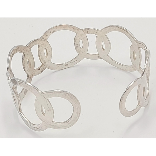 818 - A STERLING SILVER CIRCLES DESIGN BANGLE. TOTAL WEIGHT APPROX. 22G. Ref: SC 4090