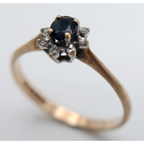 577 - A Petit 9K Yellow Gold Sapphire and Diamond Ring. A central sapphire with an eight diamond surround.... 