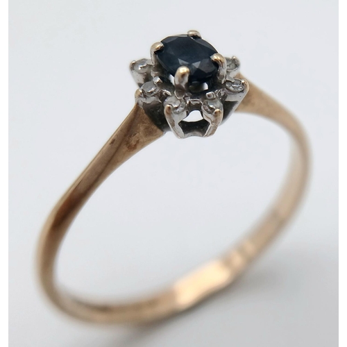 577 - A Petit 9K Yellow Gold Sapphire and Diamond Ring. A central sapphire with an eight diamond surround.... 