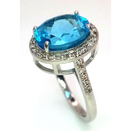 1561 - A 5ct Oval-cut Blue Topaz Ring surrounded by halo of 0.60ct diamonds accent. Set in 925 Silver. Ring... 