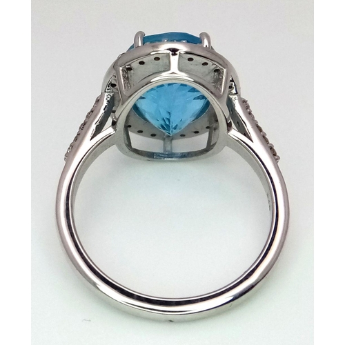 1561 - A 5ct Oval-cut Blue Topaz Ring surrounded by halo of 0.60ct diamonds accent. Set in 925 Silver. Ring... 