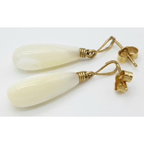 703 - A pair of 9ct gold drop earrings featuring stone pendants. Total weight: 2g , 2.6cm drop length.