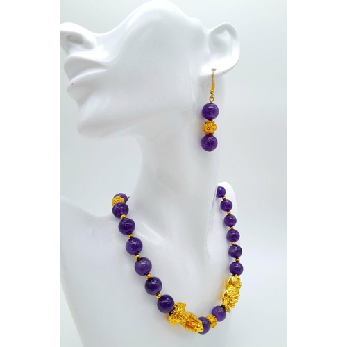 147 - A Chinese, amethyst necklace and earrings set with gold plated fu dogs and “good luck” charms. In a ... 