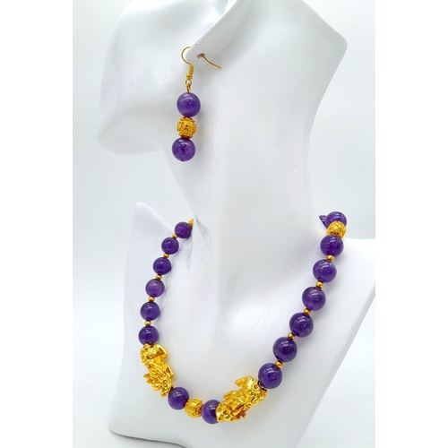 147 - A Chinese, amethyst necklace and earrings set with gold plated fu dogs and “good luck” charms. In a ... 