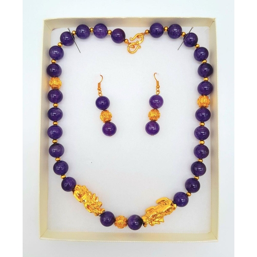 147 - A Chinese, amethyst necklace and earrings set with gold plated fu dogs and “good luck” charms. In a ... 