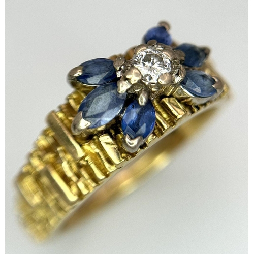 45 - An 18K Sapphire and Diamond 18k Gold Ring. Central diamond with a four petal sapphire surround. Size... 