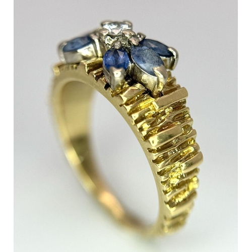 45 - An 18K Sapphire and Diamond 18k Gold Ring. Central diamond with a four petal sapphire surround. Size... 