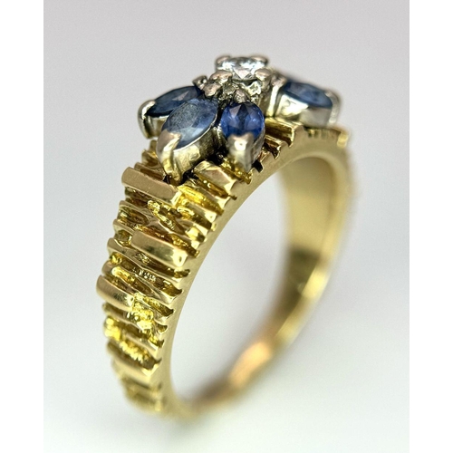 45 - An 18K Sapphire and Diamond 18k Gold Ring. Central diamond with a four petal sapphire surround. Size... 