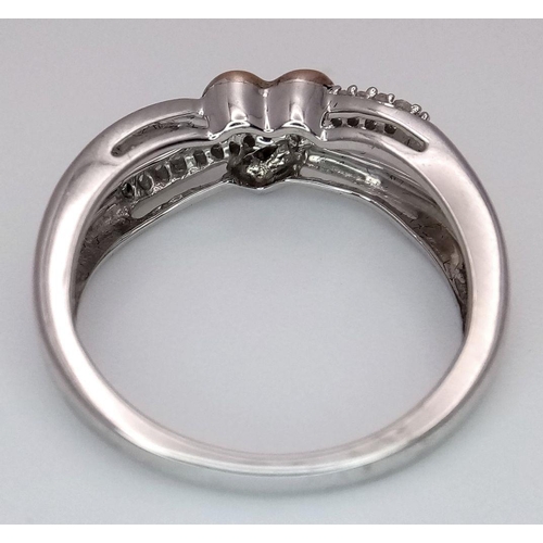 519 - A 9K White and Rose Gold Diamond Heart Crossover Ring. 0.10ctw diamonds. Size L. 2.6g total weight.