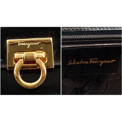 933 - A Salvatore Ferragamo Black Patent Leather Handbag. Gold tone furniture. Textile interior with zippe... 