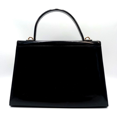 933 - A Salvatore Ferragamo Black Patent Leather Handbag. Gold tone furniture. Textile interior with zippe... 