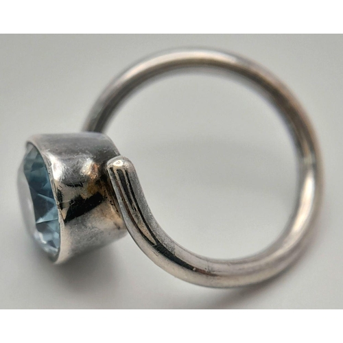 906 - A Sterling Silver Blue Topaz Set Crossover Ring Size N. Set with a 1.4cm Long Oval Cut Blue Topaz, t... 