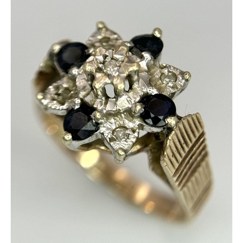 151 - A 9K YELLOW GOLD VINTAGE DIAMOND AND SAPPHIRE FLORAL FORM RING. RAISED REGAL SETTING. 5.4G. SIZE Q. ... 