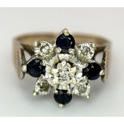 151 - A 9K YELLOW GOLD VINTAGE DIAMOND AND SAPPHIRE FLORAL FORM RING. RAISED REGAL SETTING. 5.4G. SIZE Q. ... 