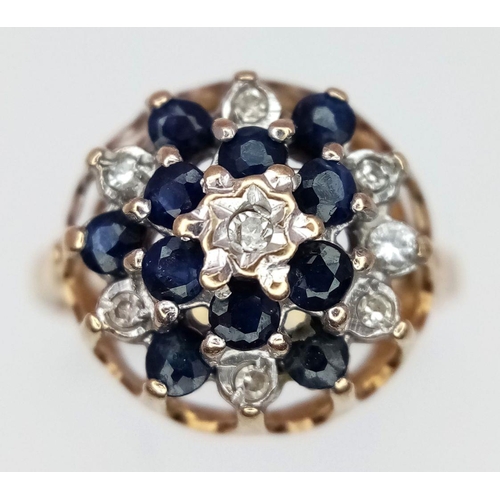 307 - A 9K YELLOW GOLD DIAMOND AND SAPPHIRE FLORAL FORM RING. RAISED SETTING. 2.6G. SIZE L. SC5067