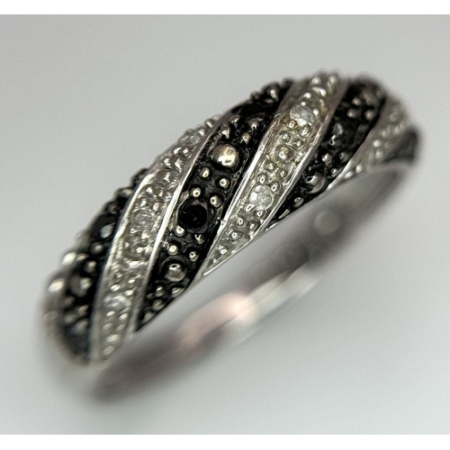 691 - A 9K WHITE GOLD, BLACK AND WHITE DIAMOND RING. 2.3G. SIZE O. SC2020