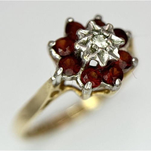 726 - A 9K YELLOW GOLD DIAMOND AND RED STONE RING - 1.9G. SIZE L 1/2. SC5036