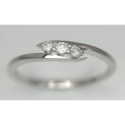 740 - A 9K WHITE GOLD DIAMOND SET THREE STONE TWIST RING. 1.5G. SIZE P. 8800