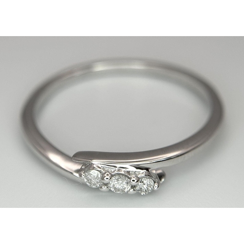 740 - A 9K WHITE GOLD DIAMOND SET THREE STONE TWIST RING. 1.5G. SIZE P. 8800