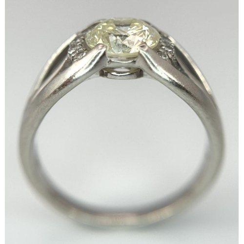 316 - A Stunning 900 Platinum 1.5ct (SI2) Tinted Yellow Diamond Ring. Brilliant round cut central diamond ... 