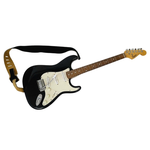 736 - A Squire Strat (by Fender) Six String Electric Black and White Guitar. Comes with a shoulder strap. ... 