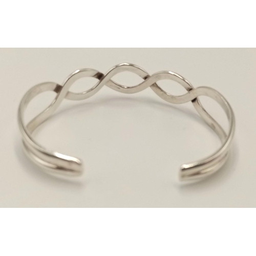 1084 - A Sterling Silver Celtic Design Knot Bangle. 6.1cm Inner Width. Weight 17.07 Grams