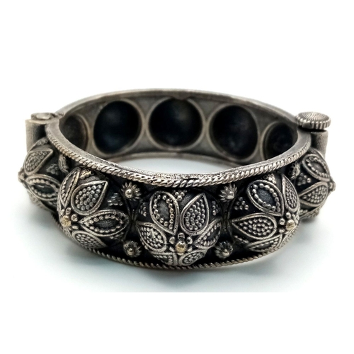 1587 - A white metal pull-out clasp bangle with intricate floral and leaf motifs. approx 6cm diameter.