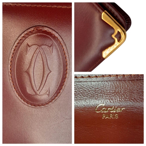 305 - A Cartier Burgundy Must de Cartier Wallet. Burgundy leather exterior, featuring gold-toned hardware ... 