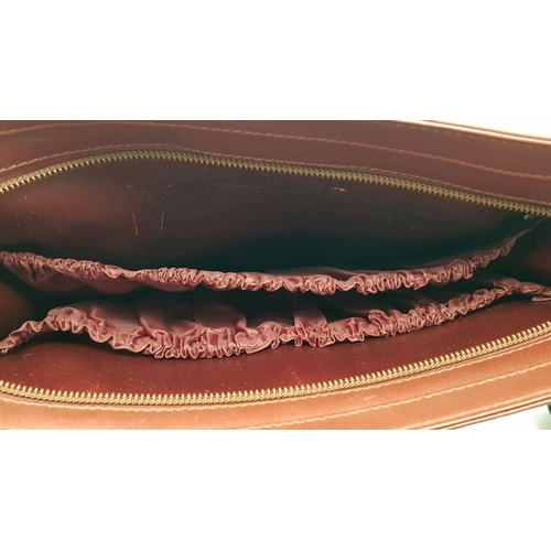 298 - A Cartier Burgundy Leather Toiletry Bag. Burgundy leather exterior with gold-toned hardware and snap... 