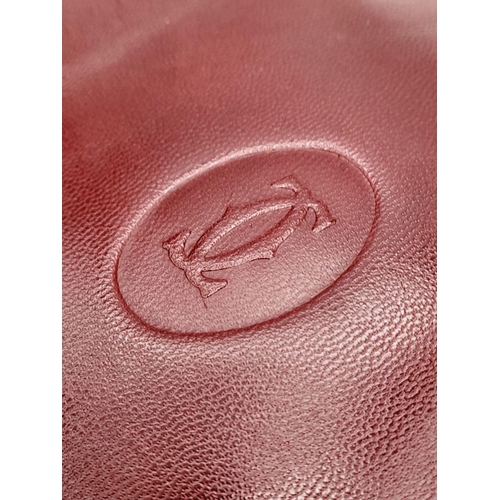 312 - A Cartier Burgundy Must de Cartier Pouch. Leather exterior with gold-toned hardware and a zip closur... 