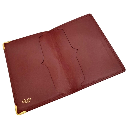 340 - A Cartier Burgundy Leather Passport Holder. Leather exterior with gold-toned hardware and an embosse... 