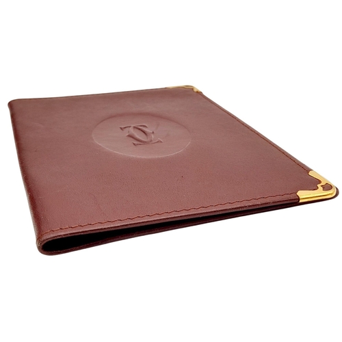 340 - A Cartier Burgundy Leather Passport Holder. Leather exterior with gold-toned hardware and an embosse... 