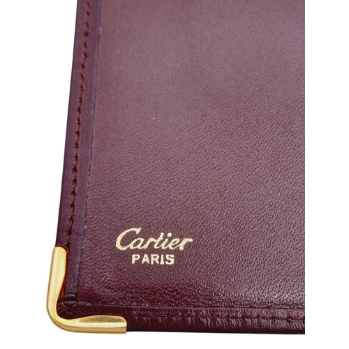 340 - A Cartier Burgundy Leather Passport Holder. Leather exterior with gold-toned hardware and an embosse... 