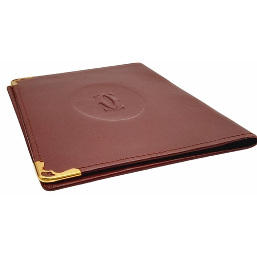 340 - A Cartier Burgundy Leather Passport Holder. Leather exterior with gold-toned hardware and an embosse... 