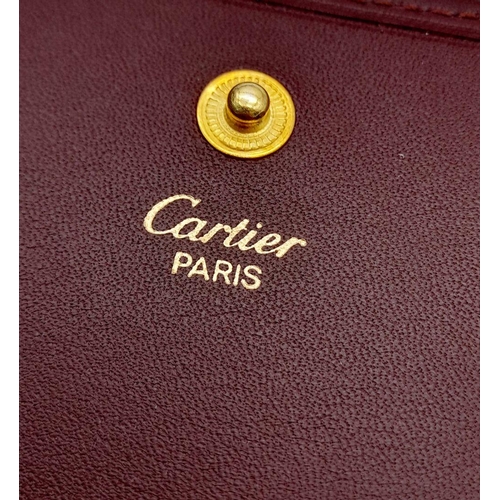 395 - A Cartier Paris Brown Leather Coin Wallet. Leather exterior with gold-toned hardware and snap button... 