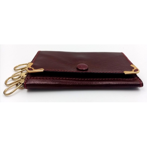 402 - A Cartier Burgundy Leather Key Holder. Leather exterior with gold-tone hardware and snap closure. Bu... 