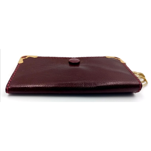 402 - A Cartier Burgundy Leather Key Holder. Leather exterior with gold-tone hardware and snap closure. Bu... 