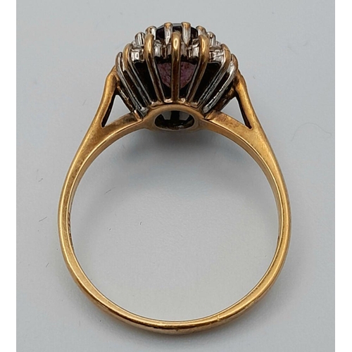 353 - A 9K GOLD RING WITH AMETHYST CENTRE STONE SURROUNDED BY A HALO OF DIAMONDS.   2.4gms    size N