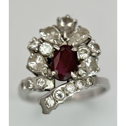 59 - A Vintage 18K White Gold, Ruby and Diamond Ring. An oval ruby with an abstract diamond surround of p... 