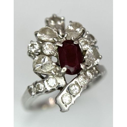 59 - A Vintage 18K White Gold, Ruby and Diamond Ring. An oval ruby with an abstract diamond surround of p... 